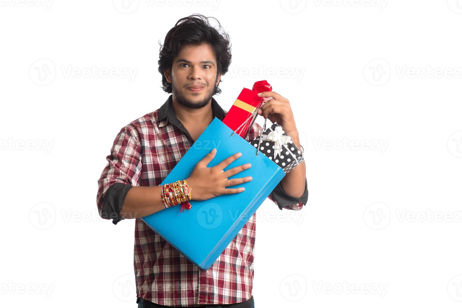 jeunes hommes montrant rakhi sur sa main avec des sacs à provisions et une boîte-cadeau à l'occasion du festival raksha bandhan. photo