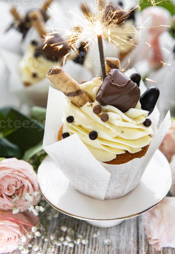 cupcakes au chocolat avec des cierges magiques sur fond de bois blanc photo