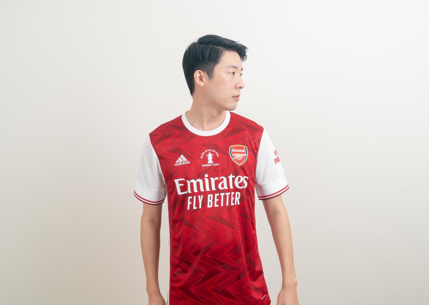 bangkok, thaïlande - 27 novembre 2021 - jeune homme asiatique portant une chemise d'arsenal avec un fond blanc. photo