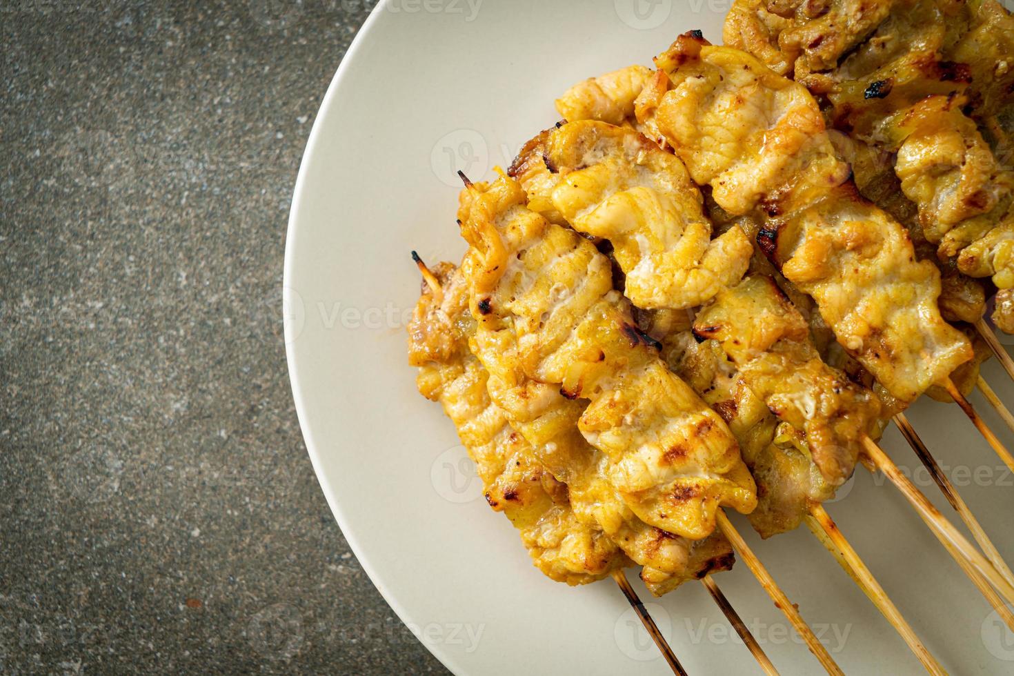 satay de porc avec des cornichons à la sauce aux arachides qui sont des tranches de concombre et des oignons au vinaigre photo