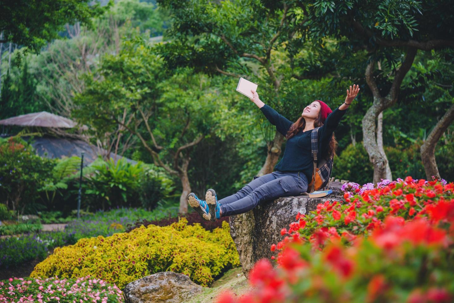 femme voyage nature dans le jardin fleuri. détendez-vous assis sur des rochers et lisez des livres au milieu de la nature au parc national doi inthanon. photo