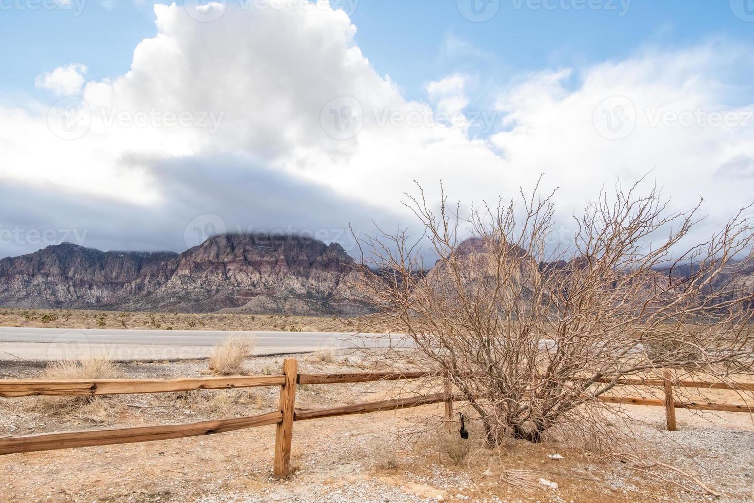 un arbre et une clôture avec des nuages venant au-dessus des montagnes de Red Rock Canyon à Las Vegas, nv photo