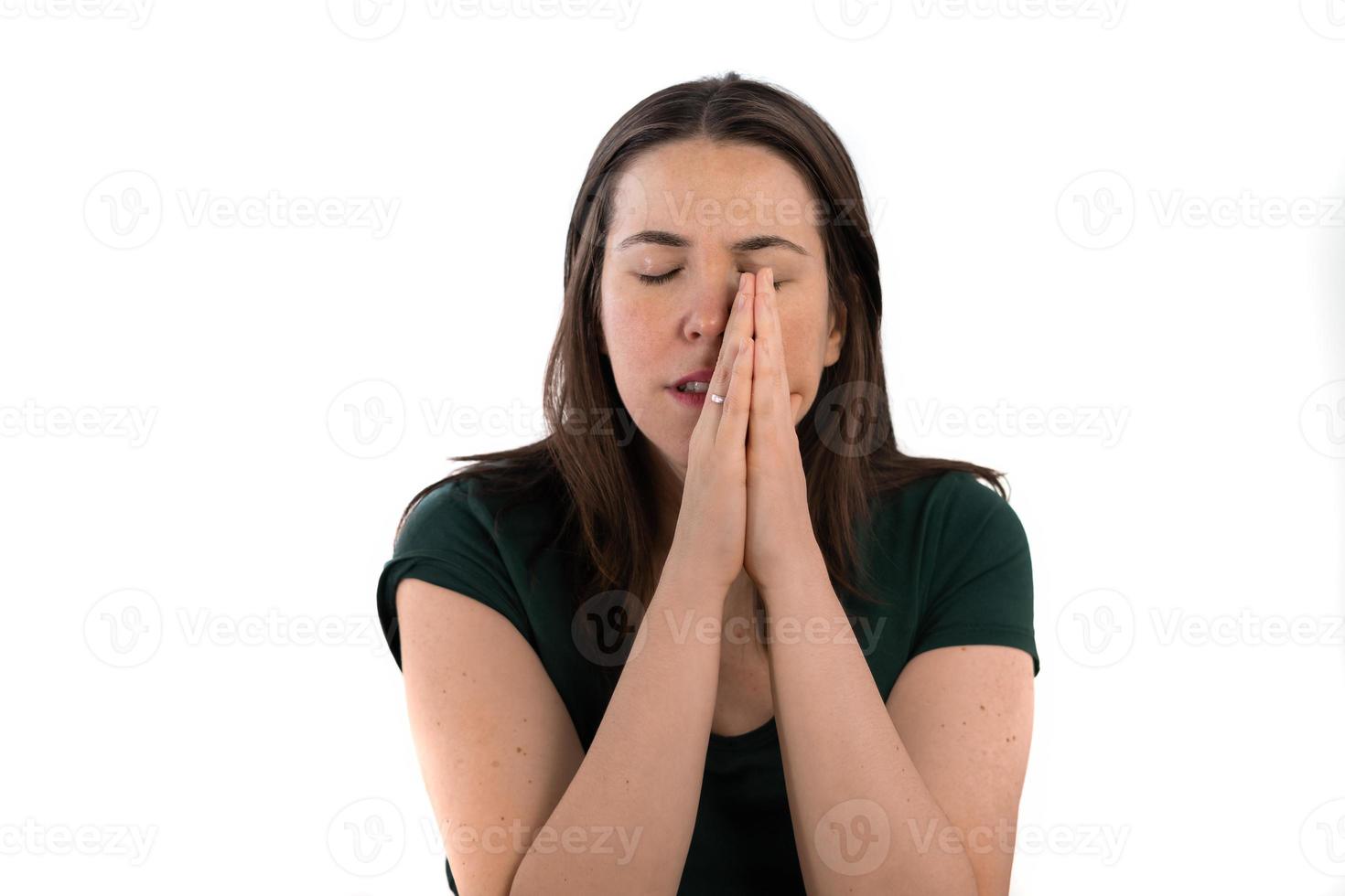 jeune fille aux cheveux longs avec ses mains jointes sur son visage en prière photo