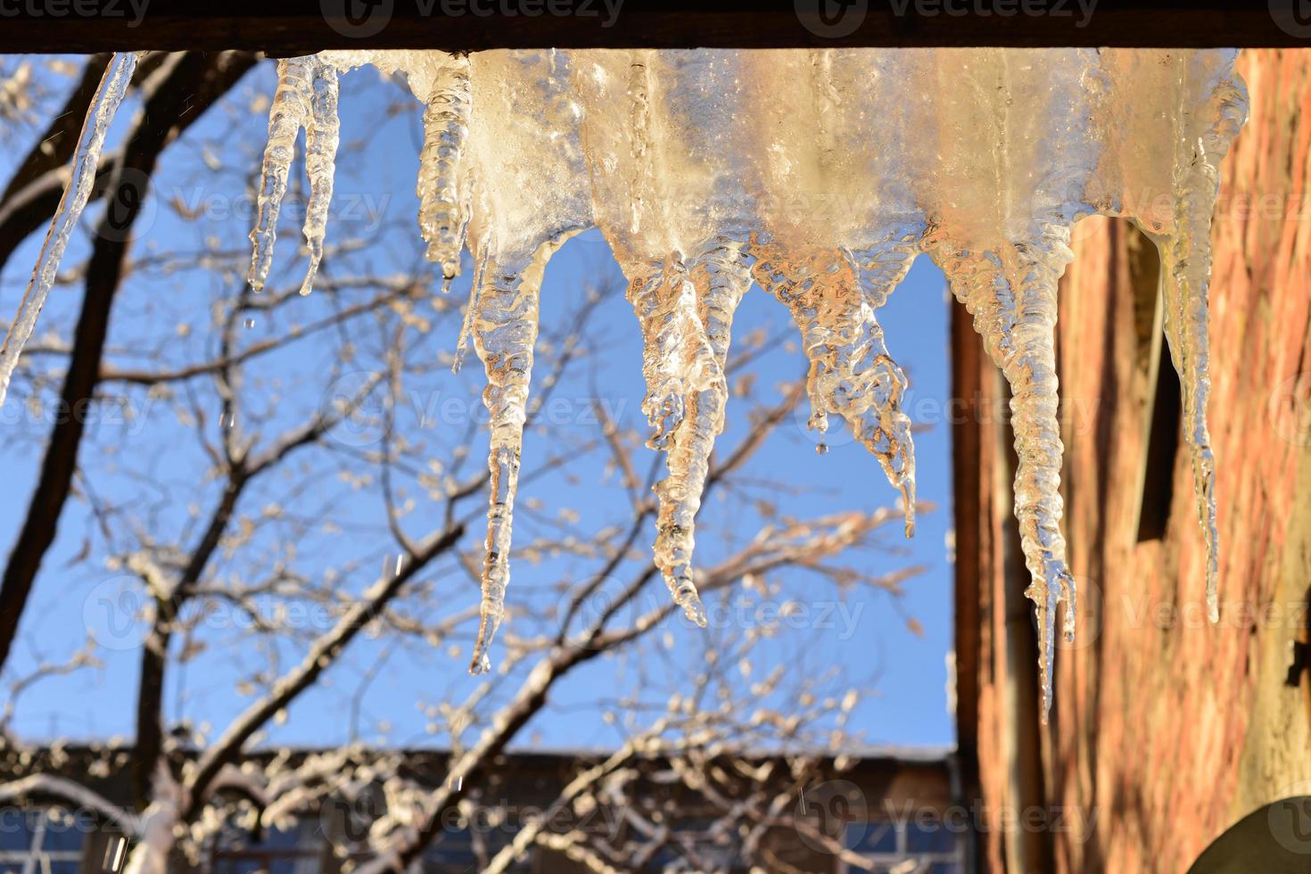 la fonte des glaçons qui pendent du toit avec fond de ciel bleu. journée ensoleillée. chaude journée d'hiver photo