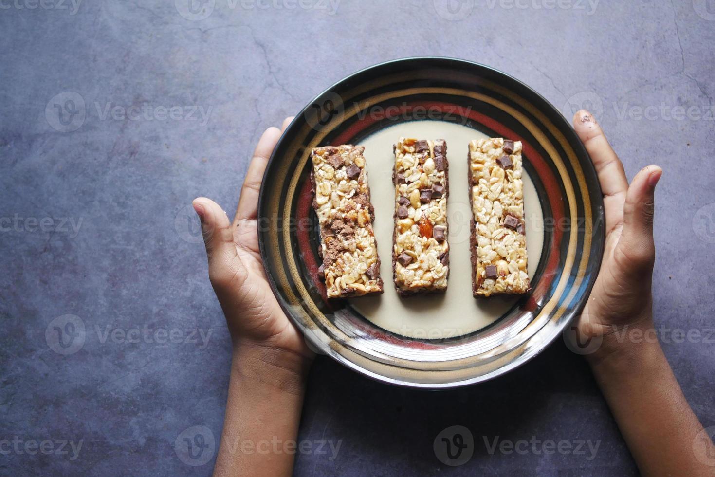 cueillir à la main des barres protéinées aux amandes, aux raisins secs et à l'avoine sur la table photo