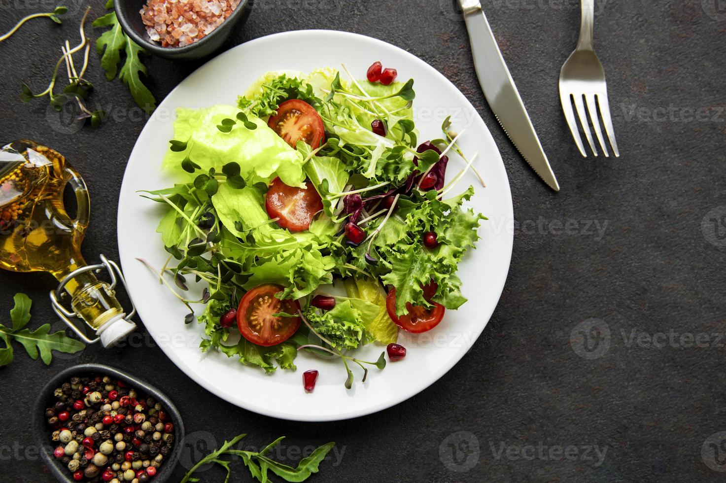 saladier vert frais avec tomates et micro-pousses sur fond de béton noir. nourriture saine, vue de dessus. photo