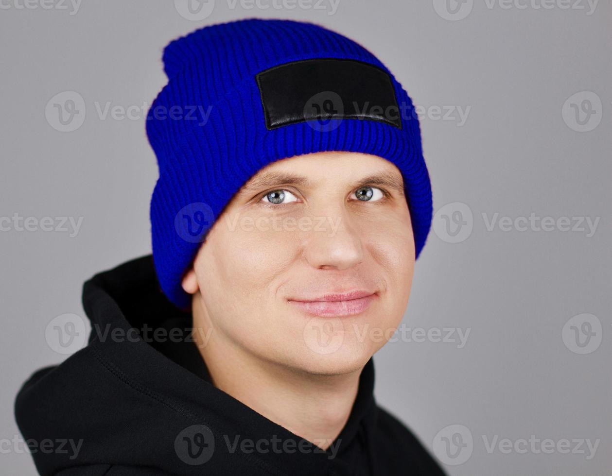 hipster dans un chapeau bleu et un sweat à capuche avec une capuche sur fond gris photo