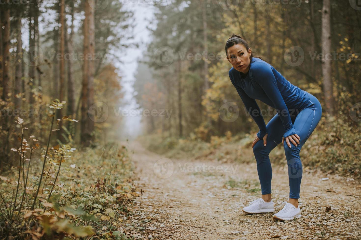 jeune femme faire une pause pendant l'exercice en plein air sur le sentier forestier à l'automne photo