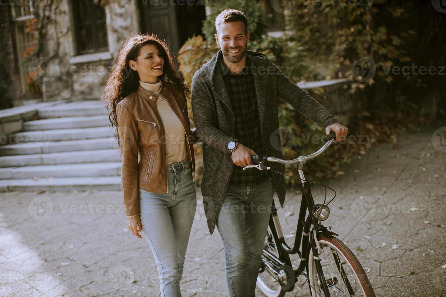 Jeune couple marchant à vélo dans le parc d'automne photo