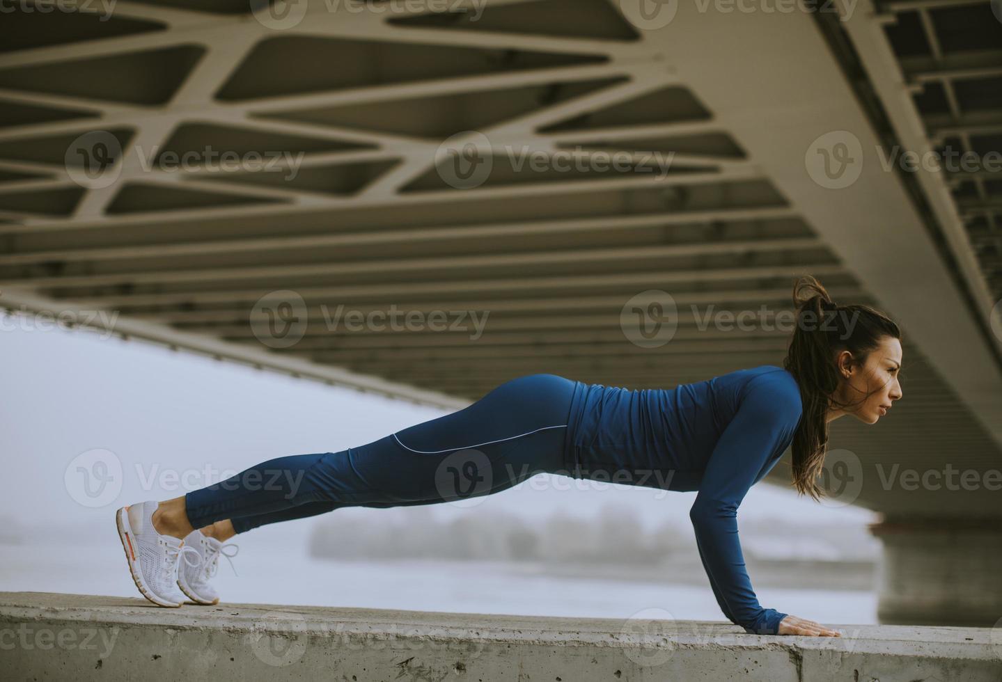 Jeune femme en survêtement bleu faisant des pompes en milieu urbain photo