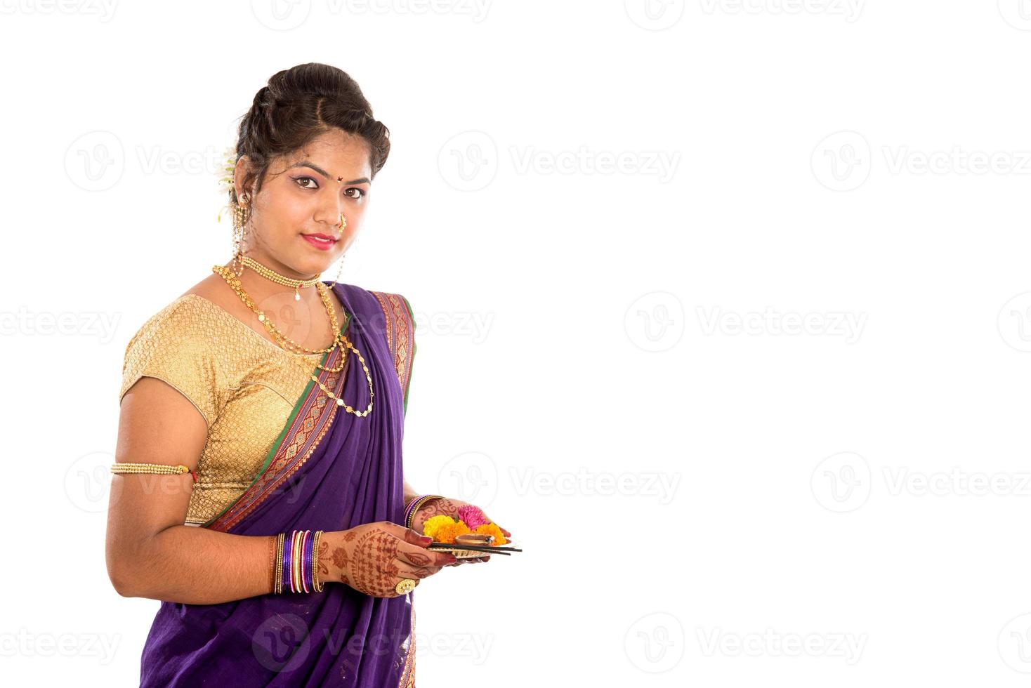 portrait d'une fille traditionnelle indienne tenant une photo de pooja thali avec diya, diwali ou deepavali avec des mains féminines tenant une lampe à huile pendant le festival de la lumière sur fond blanc