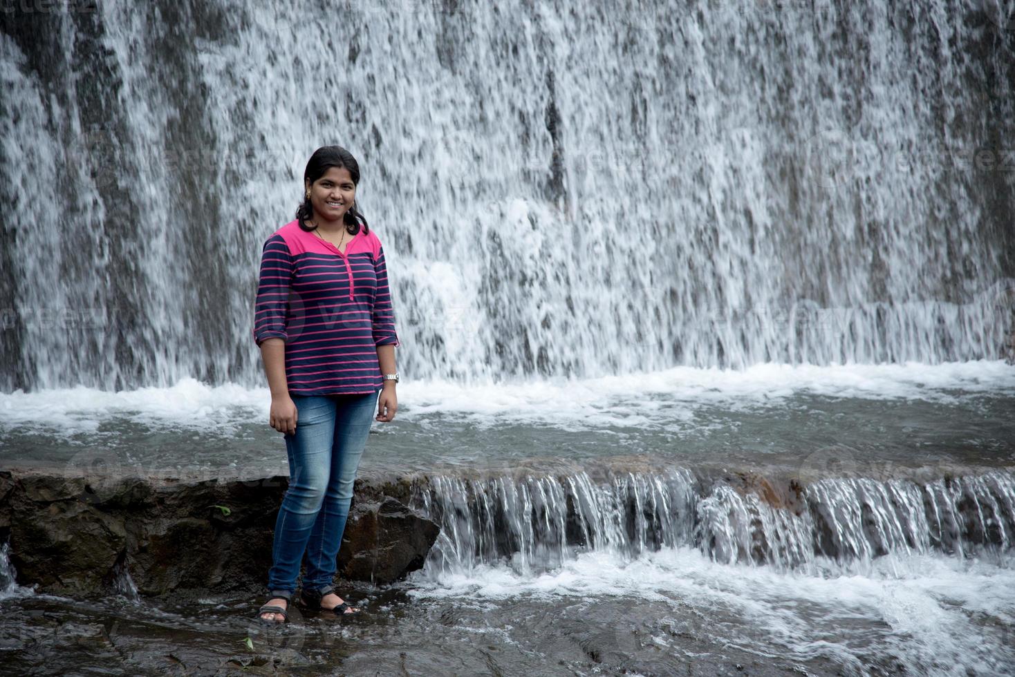 une belle jeune femme posant au bord de la rivière et profitant ou jouant avec le débordement de l'eau de la rivière. photo