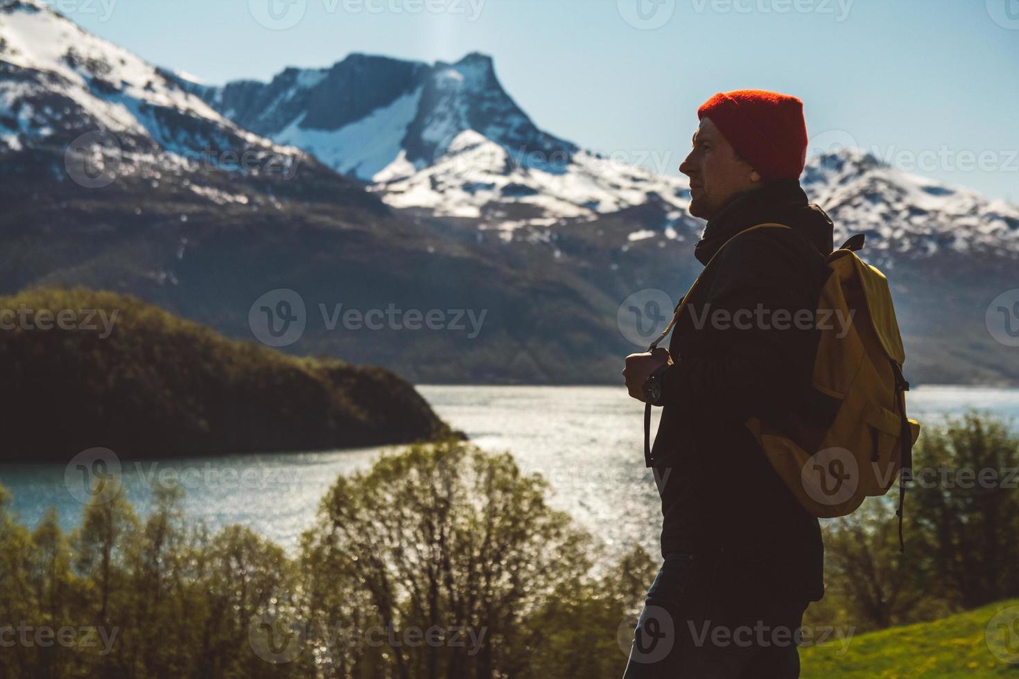 jeune homme avec un sac à dos debout sur le fond des montagnes et du lac. espace pour votre message texte ou contenu promotionnel. concept de mode de vie de voyage photo