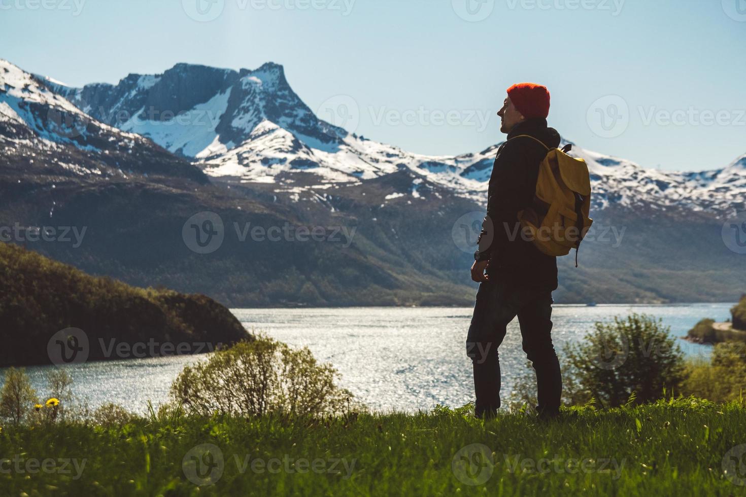 jeune homme avec un sac à dos debout sur le fond des montagnes et du lac. espace pour votre message texte ou contenu promotionnel. concept de mode de vie de voyage photo