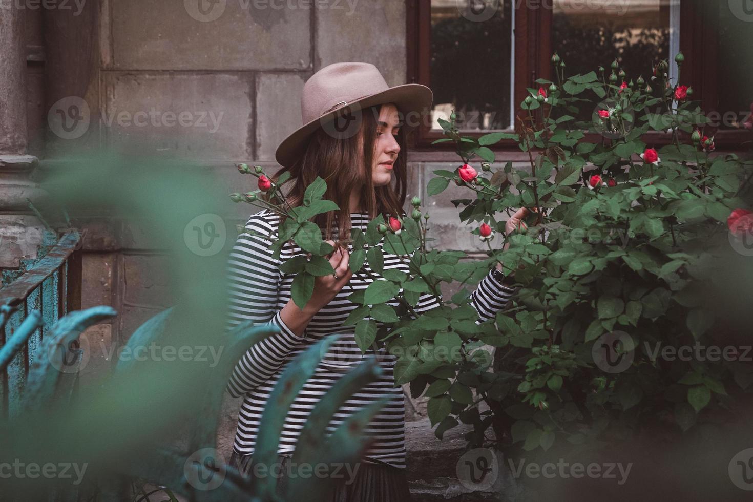 portrait de jeune femme belle au chapeau près de fleurs roses photo