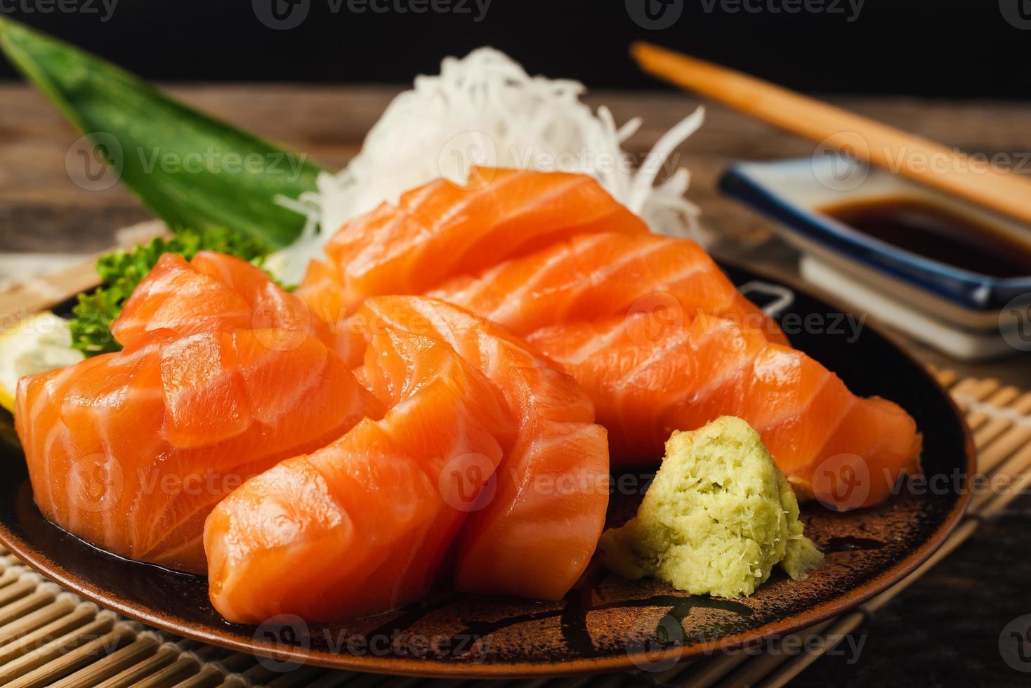 sashimi, saumon, baguettes japonaises et wasabi sur la table en bois photo