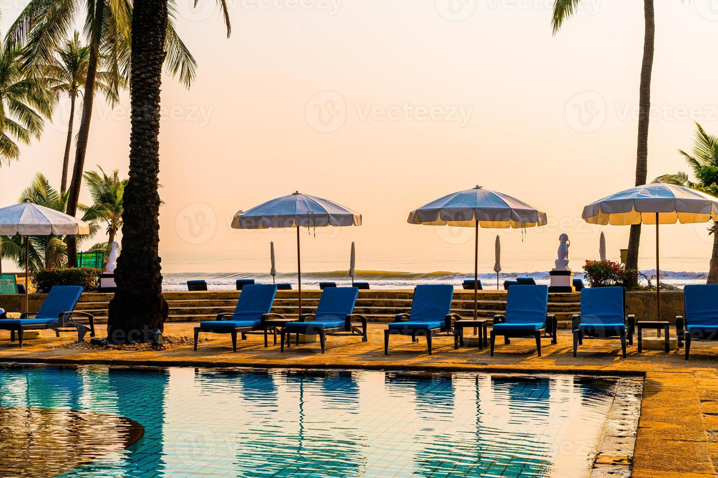 palmier avec chaise parapluie piscine dans un hôtel de luxe au lever du soleil photo