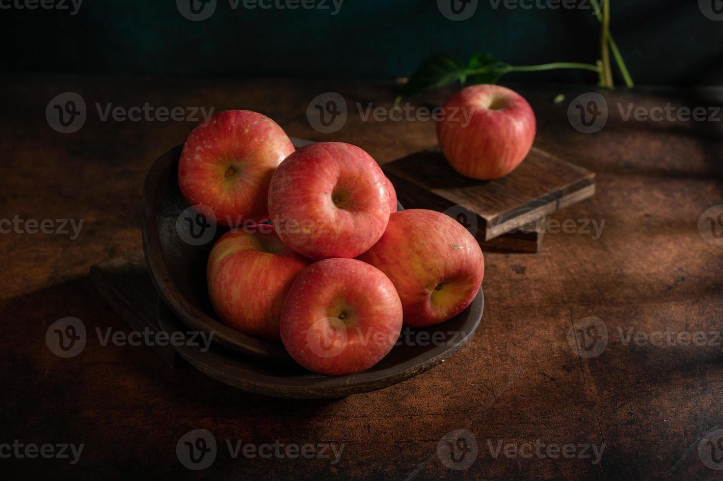 les pommes sur l'assiette ressemblent à des peintures à l'huile sous la faible lumière sur la table à grain de bois photo