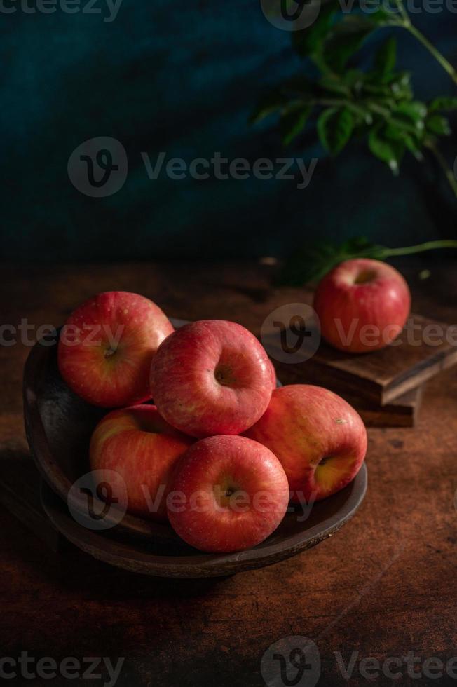 les pommes sur l'assiette ressemblent à des peintures à l'huile sous la faible lumière sur la table à grain de bois photo