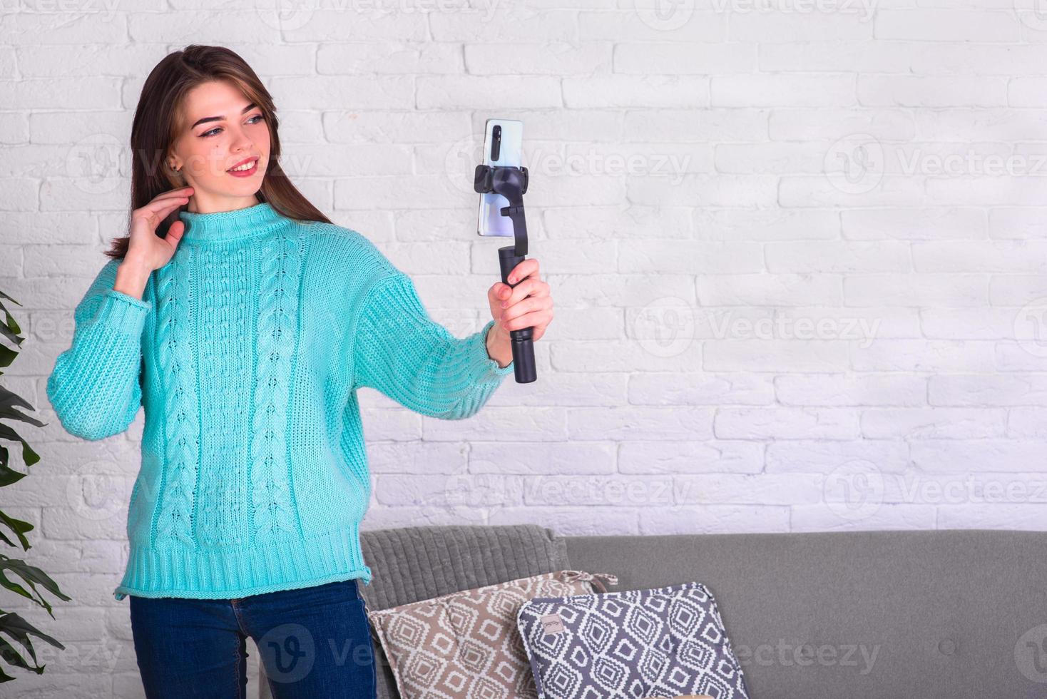 une belle fille communique avec un smartphone via une liaison vidéo depuis la maison. environnement de la maison. communiquer avec des amis en quarantaine. blogueur à domicile. photo