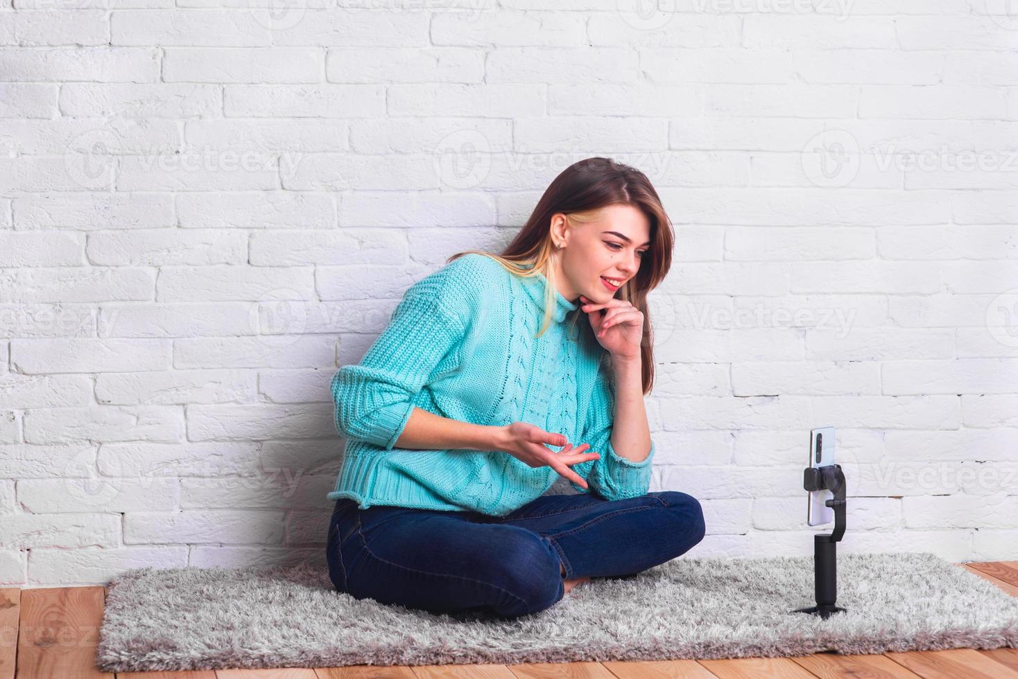 une belle fille communique avec un smartphone via une liaison vidéo depuis la maison. environnement de la maison. communiquer avec des amis en quarantaine. blogueur à domicile. photo