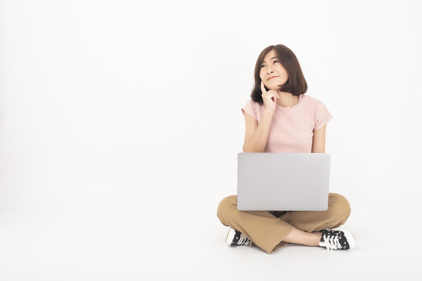 jolie femme adolescente asiatique travaille avec un ordinateur sur fond blanc photo