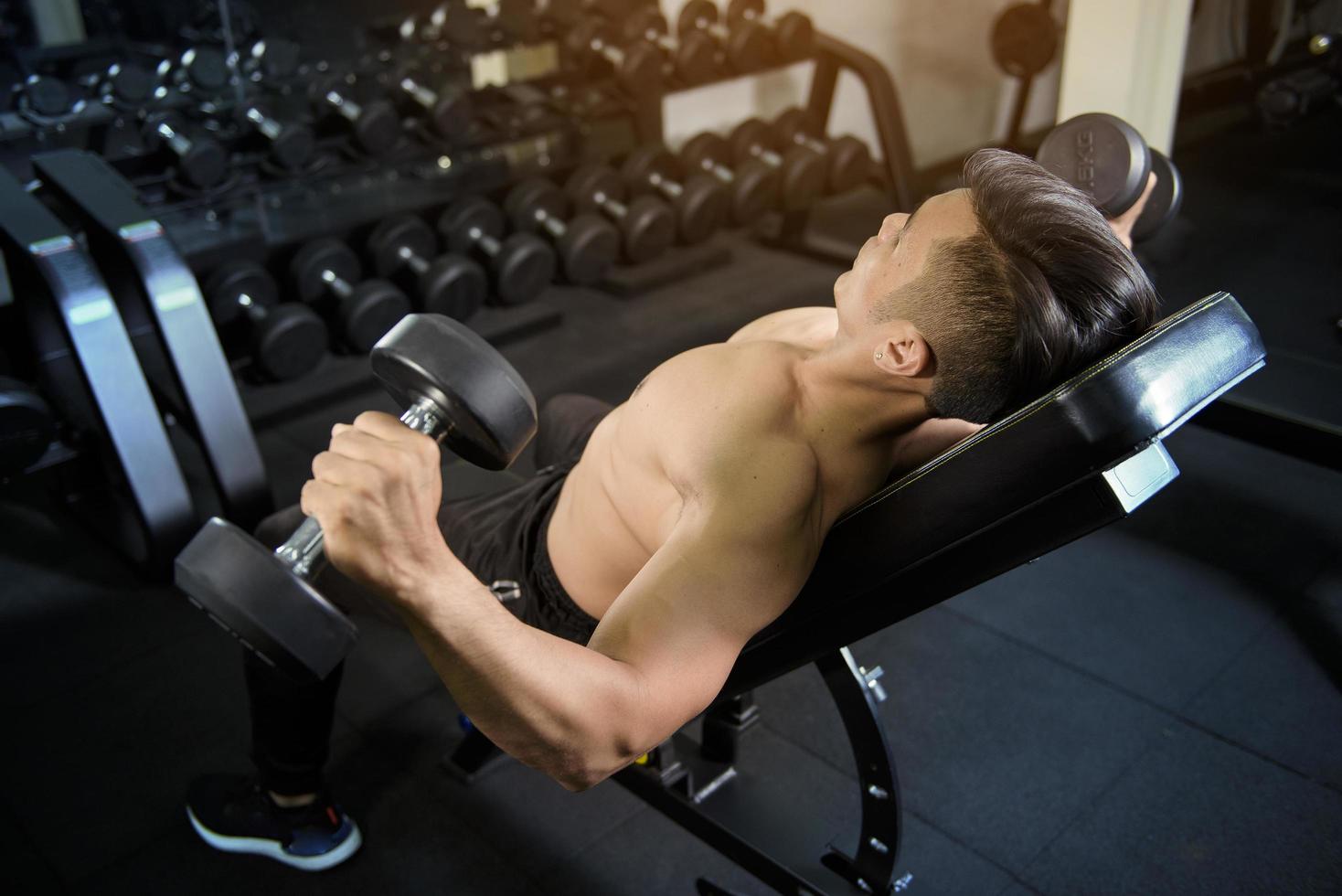 Le bodybuilder de l'homme de remise en forme musculaire est une séance d'entraînement avec des haltères dans une salle de sport photo