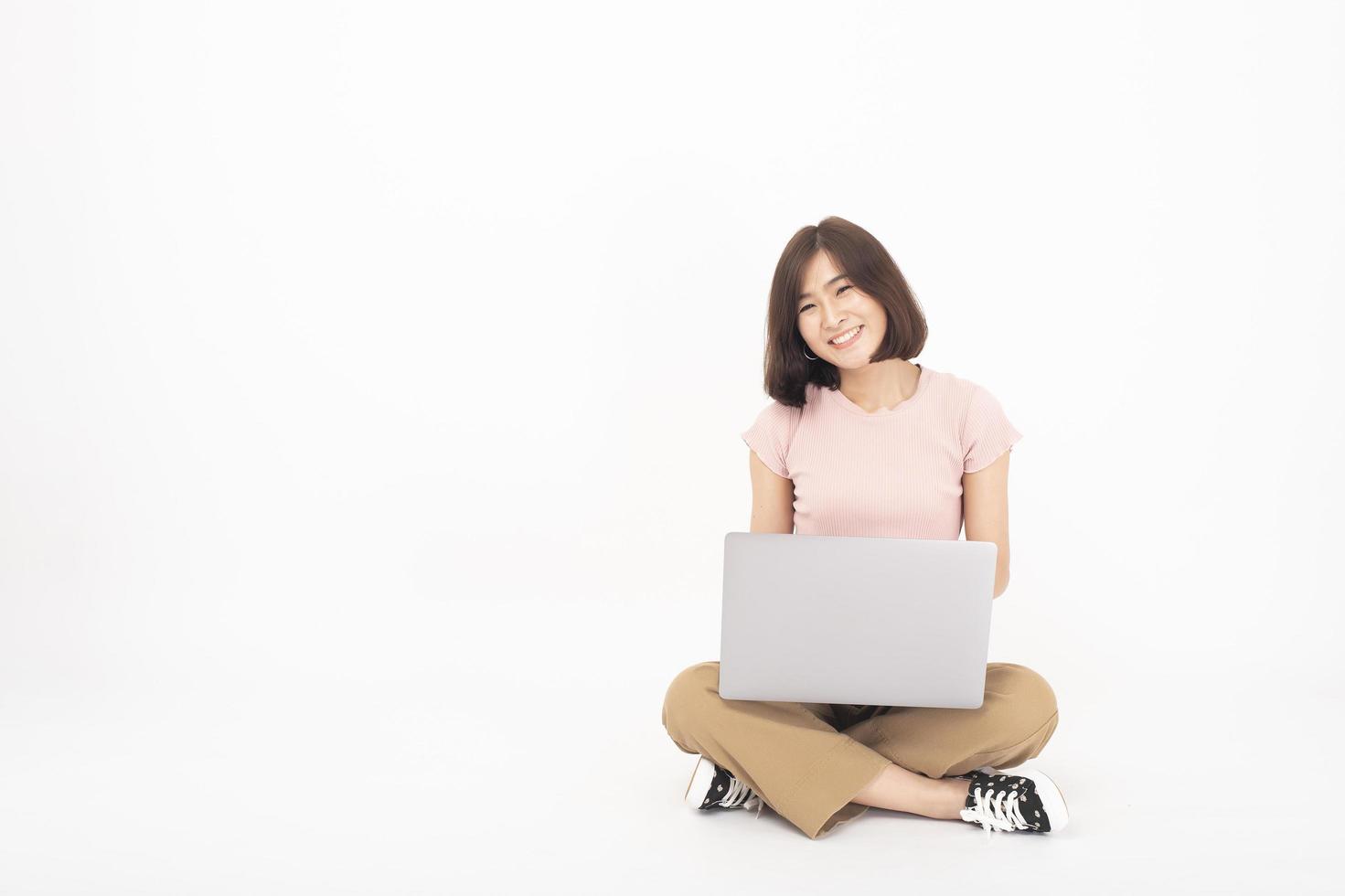 jolie femme adolescente asiatique travaille avec un ordinateur sur fond blanc photo