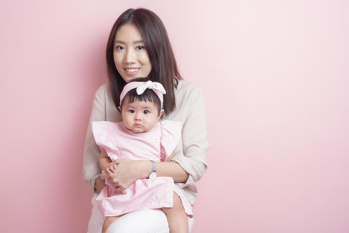 mère asiatique et adorable petite fille sont heureuses sur fond rose photo