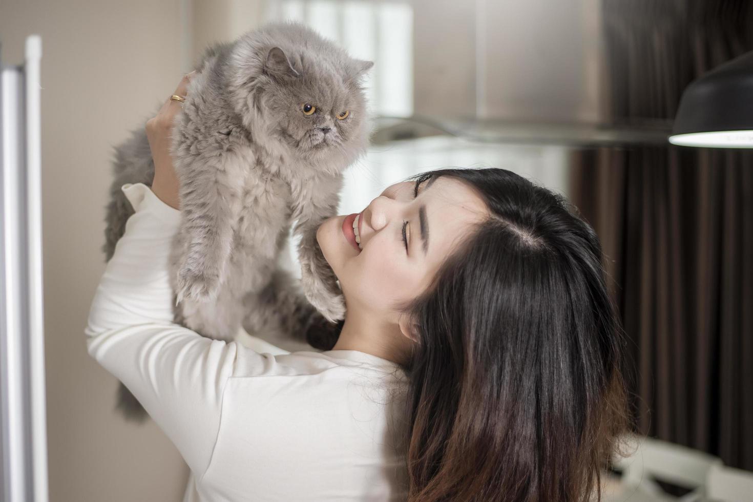 belle femme amoureuse des chats asiatiques joue avec un chat dans sa chambre photo