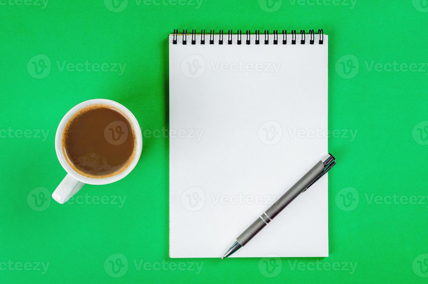 bloc-notes avec des pages blanches blanches, un stylo et une tasse de café sur fond vert clair. photo