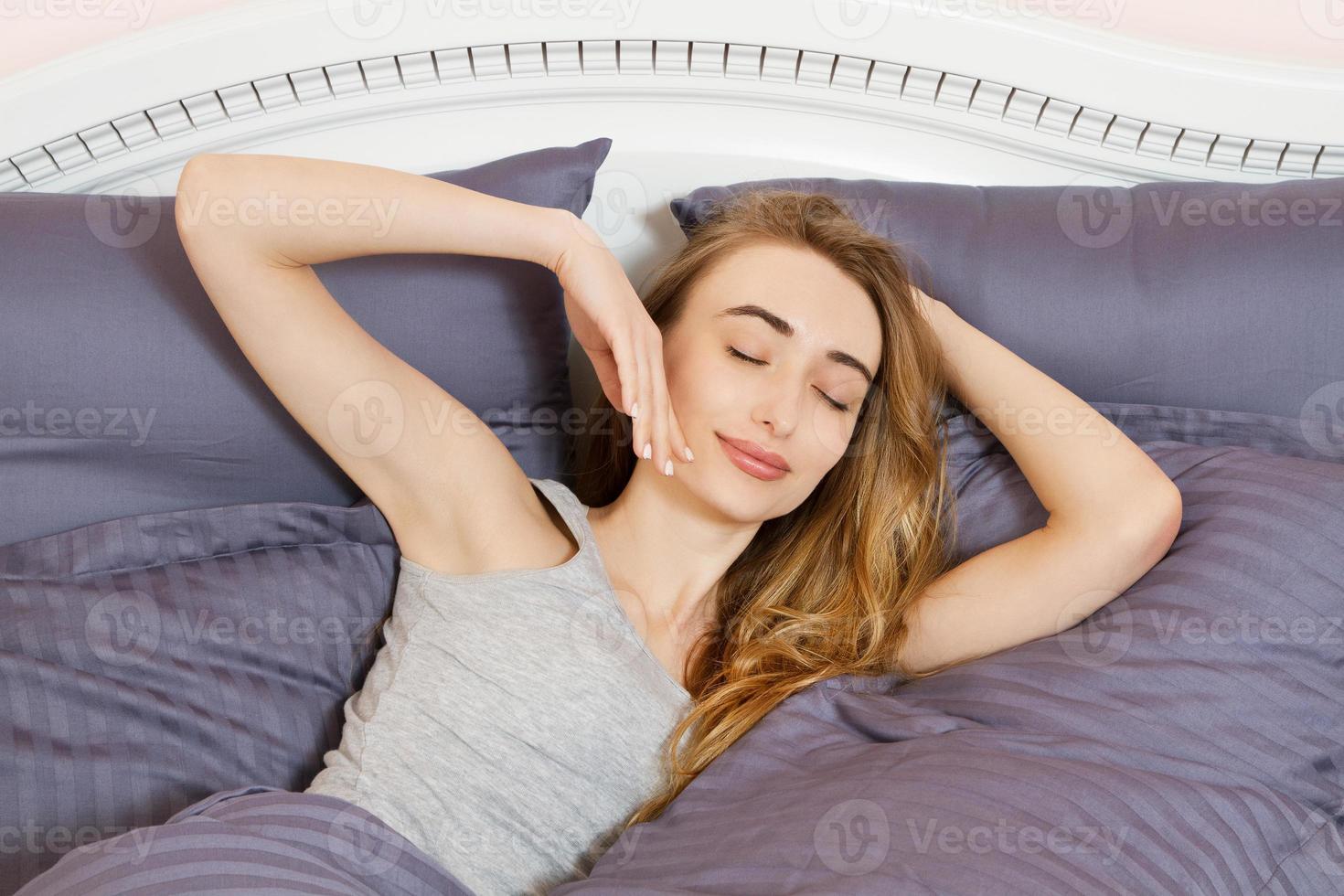 gros plan fille heureuse se réveillant sur le lit le matin - visage de sommeil de femme de fille photo