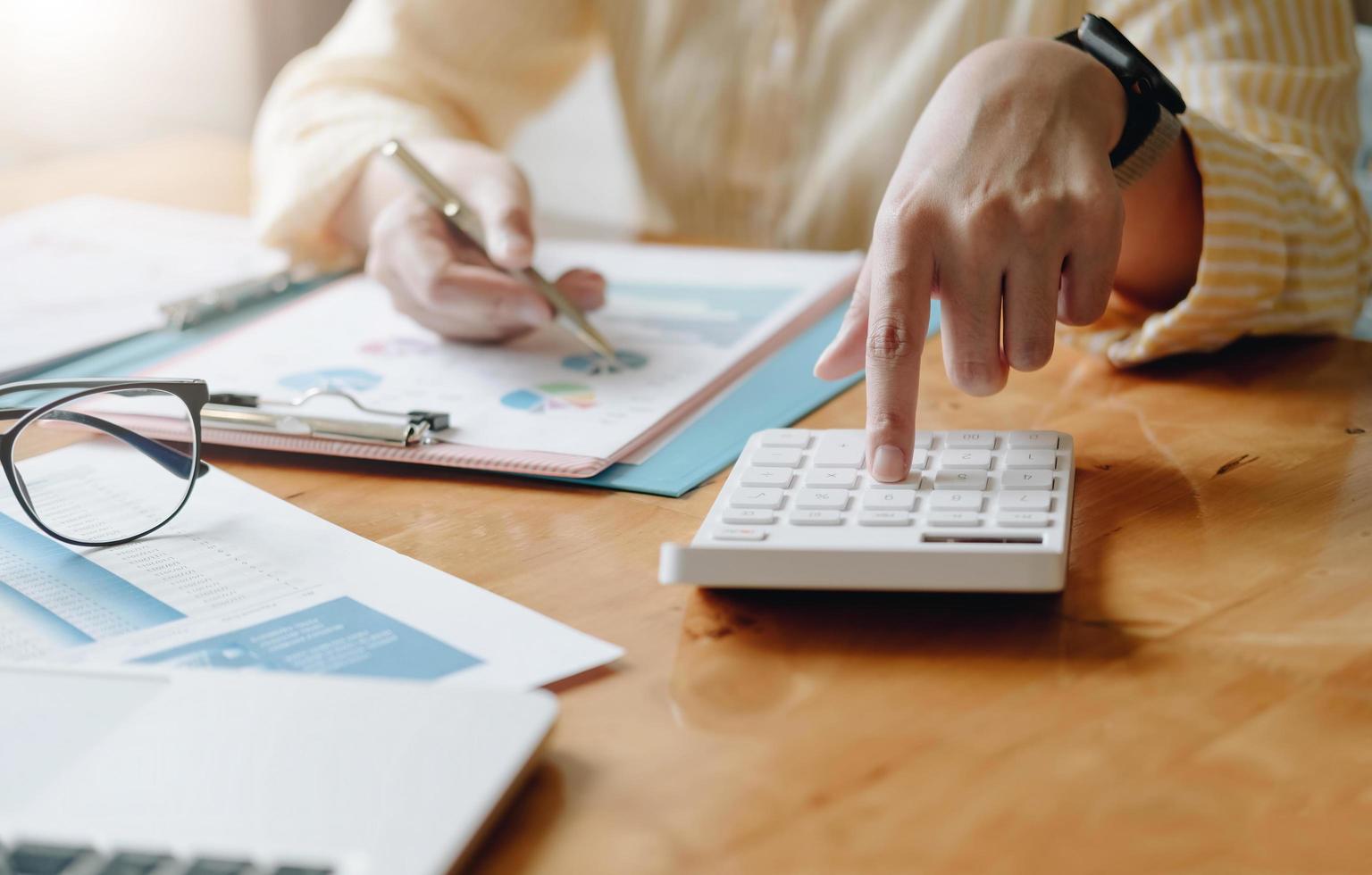 femme d'affaires comptable faisant un audit de travail et calculant les dépenses rapport financier annuel du bilan financier, faisant des finances en prenant des notes sur l'inspection de vérification du papier. photo