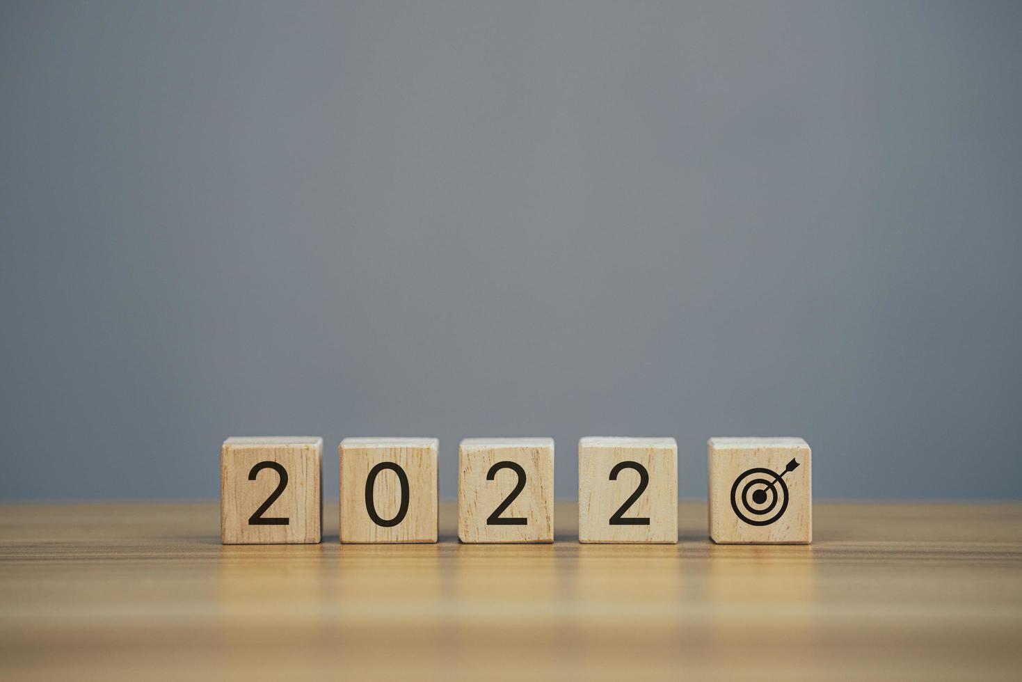 cube de bois en gros plan avec le mot d'icône de nouvel an 2022 et l'icône de cible d'objectif. photo