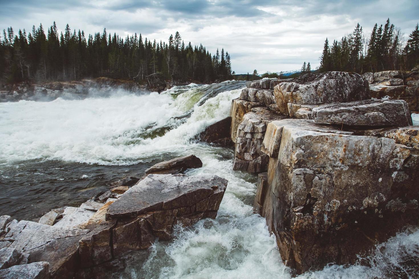 vagues et éclaboussures de rivière de montagne sur fond de forêt et ciel dramatique. paysage d'eau de rivière de forêt. rivière sauvage dans le panorama de la forêt de montagne photo