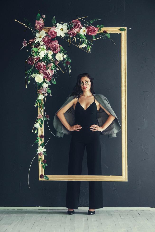 fille à la mode en veste gris foncé et lunettes posant avec fond noir grand cadre. copie, espace vide pour le texte photo