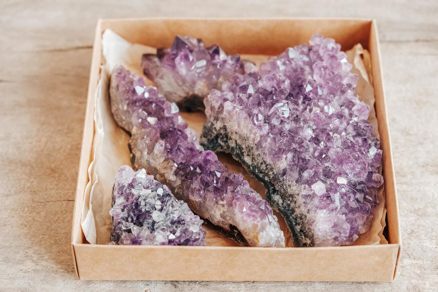 cristaux d'améthyste violet dans une boîte en papier kraft sur fond de bois photo