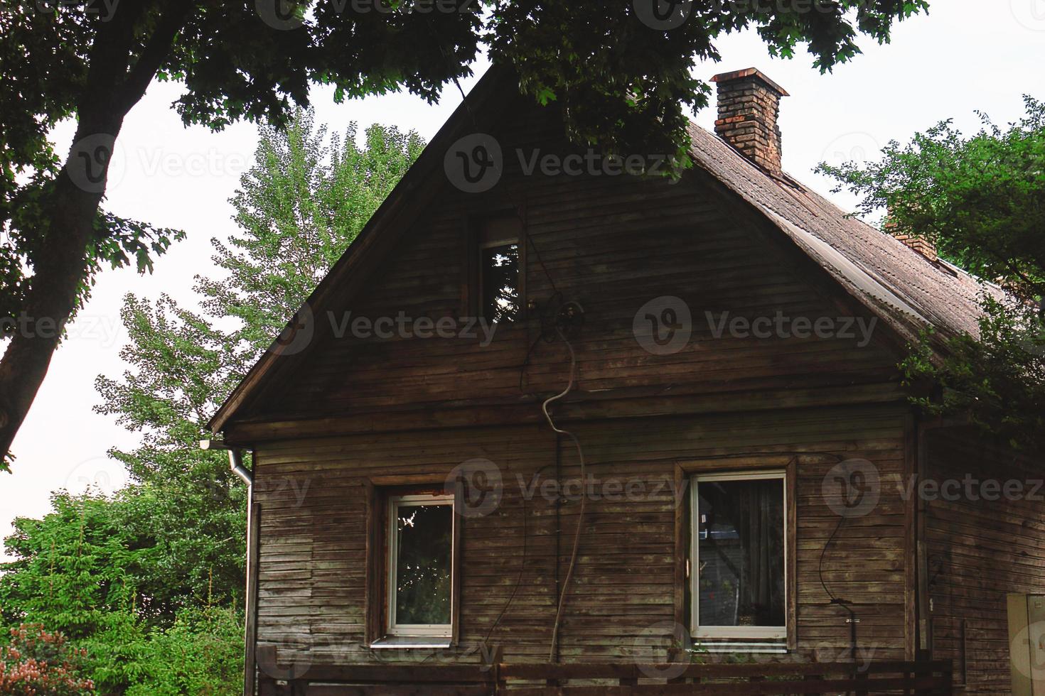 vieille maison en bois debout sous un arbre entouré de verdure photo