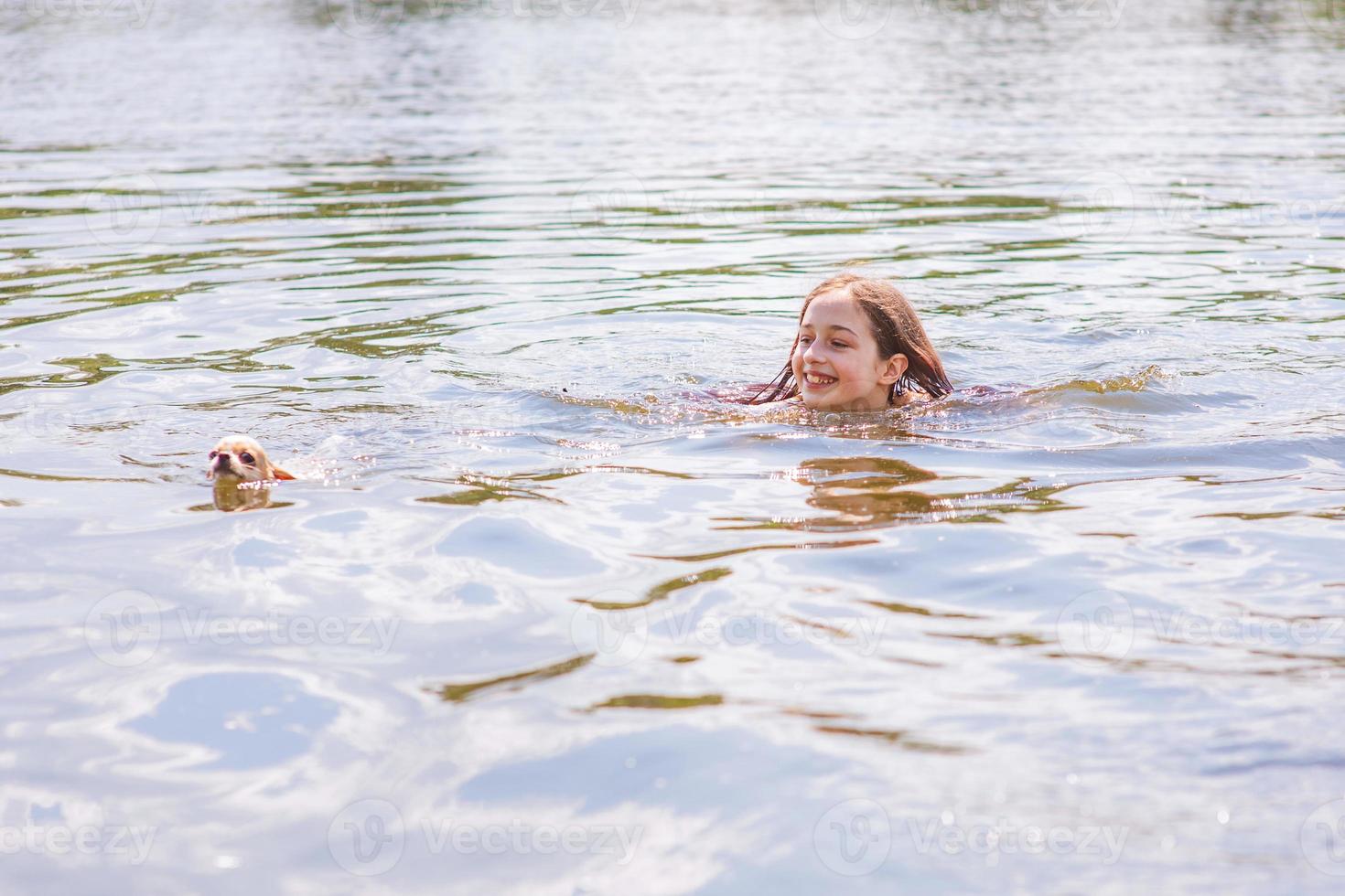 Une adolescente nage dans la rivière avec un chien chihuahua en été. enfant heureux se baigne. photo