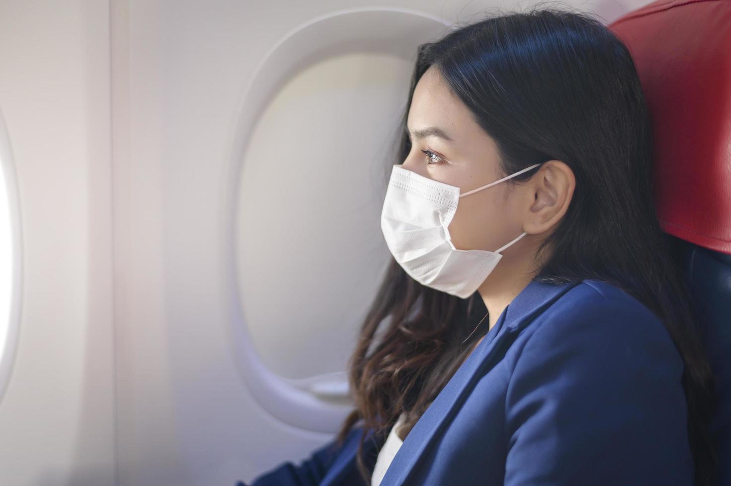 une jeune femme d'affaires porte un masque de protection à bord de l'avion, voyage sous la pandémie de covid-19, voyages de sécurité, protocole de distanciation sociale, nouveau concept de voyage normal photo