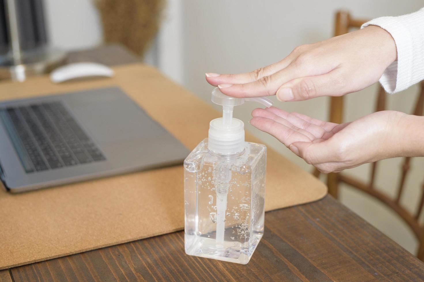 une femme applique un gel désinfectant sur les mains sur un bureau photo