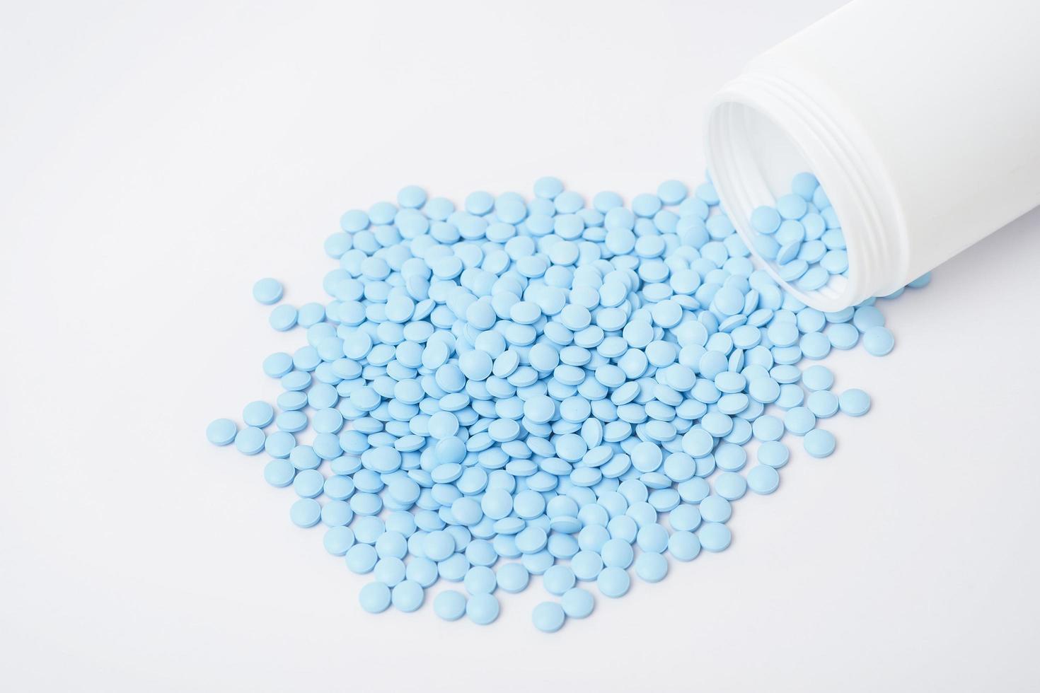 des tas de pilules bleues sur fond blanc photo