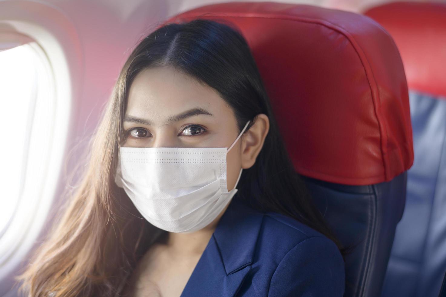 une jeune femme d'affaires porte un masque de protection à bord de l'avion, voyage sous la pandémie de covid-19, voyages de sécurité, protocole de distanciation sociale, nouveau concept de voyage normal photo