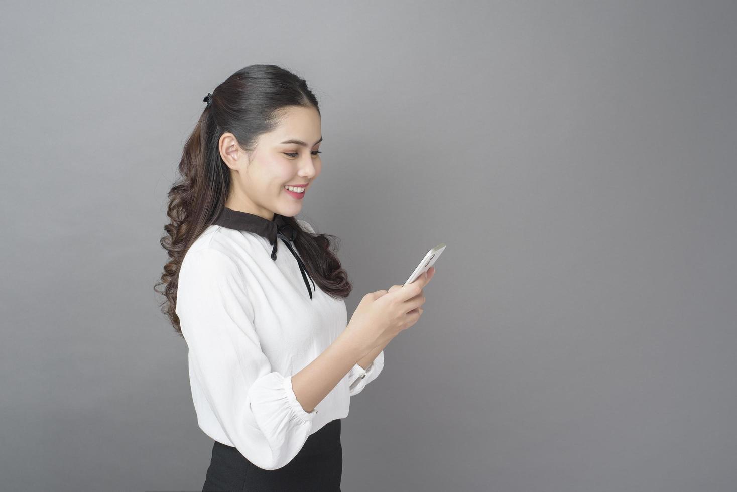 portrait de belle femme d'affaires utilise un téléphone portable en studio photo