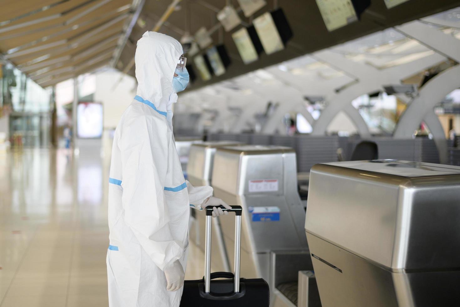 un homme asiatique porte un costume ppe à l'aéroport international, voyage en toute sécurité, protection contre le covid-19, concept de distanciation sociale photo