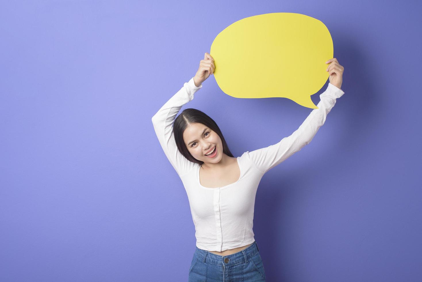 jeune femme tient un discours vide jaune sur fond violet photo