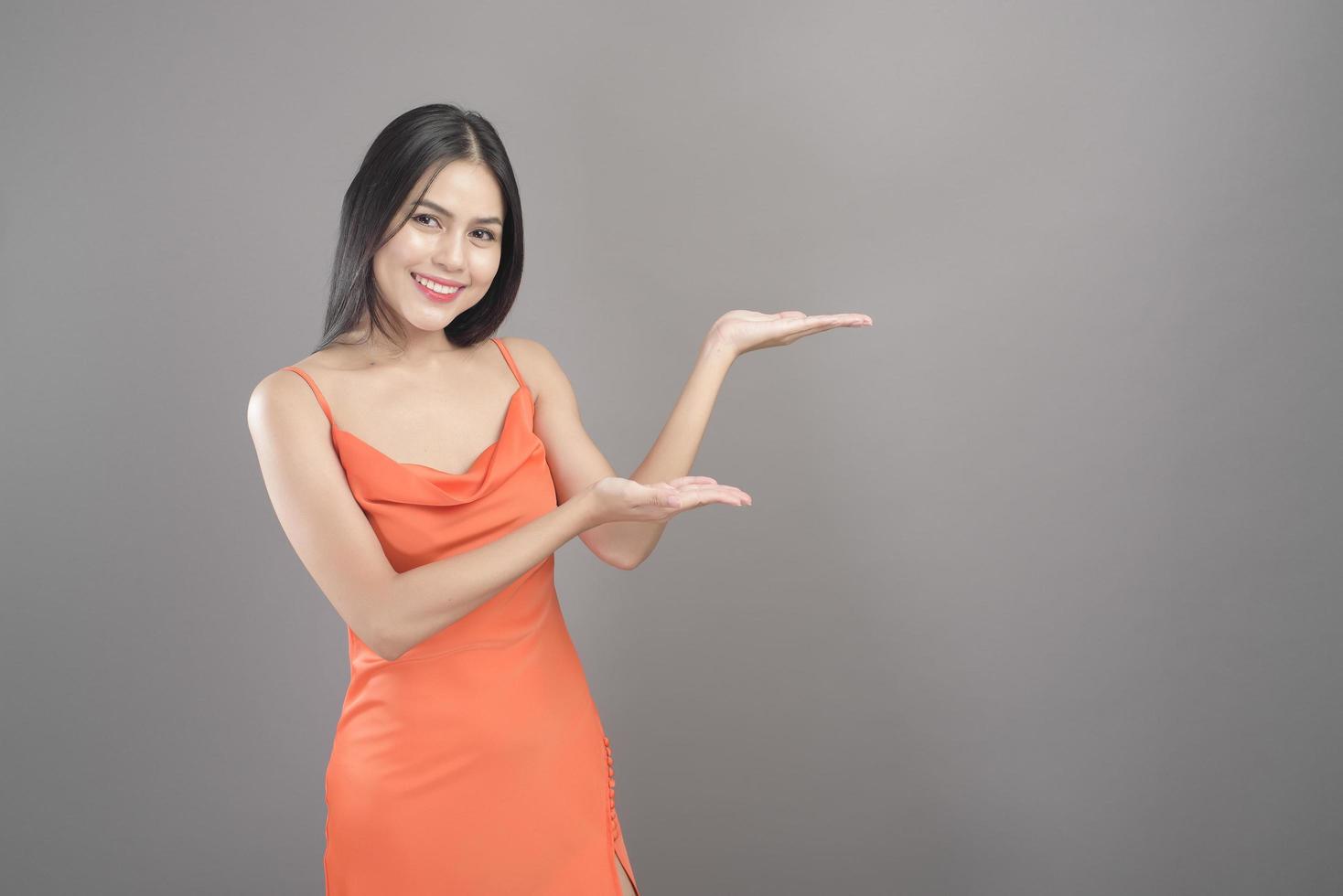 portrait de mode d'une belle femme vêtue d'une robe orange isolée sur fond gris studio photo