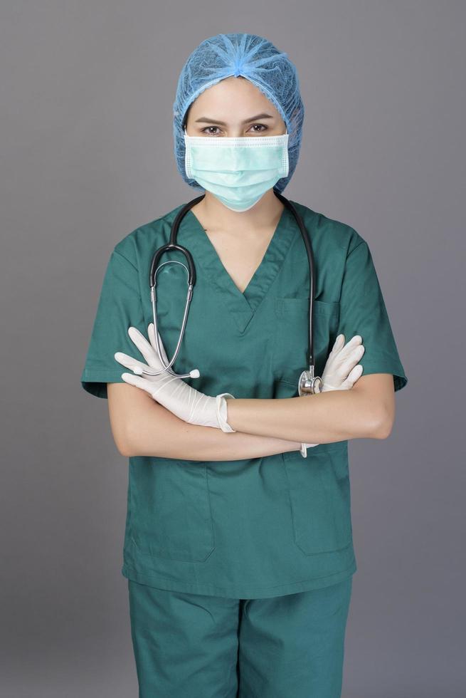 jeune femme médecin confiante en gommages verts porte un masque chirurgical sur fond gris studio photo