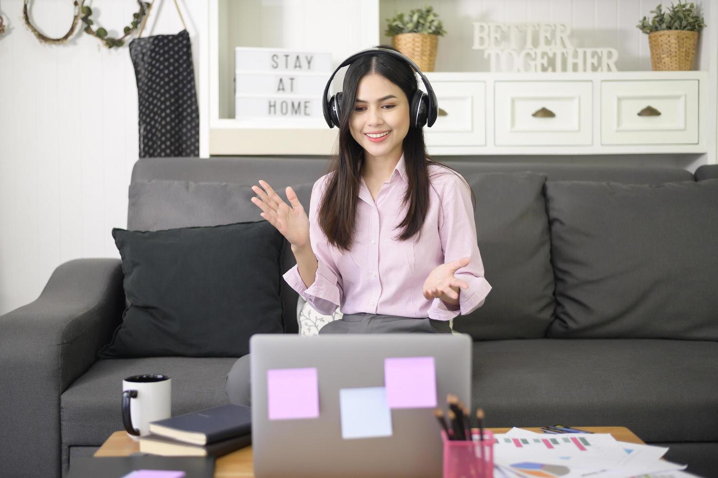 une belle jeune femme portant un casque fait une vidéoconférence via un ordinateur à la maison, concept de technologie d'entreprise. photo