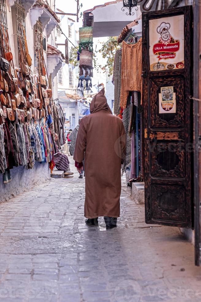 vêtements et sac à main accrochés au mur à vendre dans une rue étroite photo